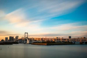 Long exposure sunset photography of Rainbow Bridge in Odaiba, Tokyo featuring racing clouds.