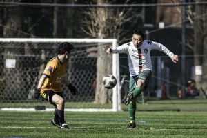 soccer player kicks ball past defender