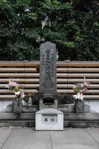 The memorial tomb of Taira no Masakado in Otemachi, Tokyo, decorated with flowers and offerings against a backdrop of trees.