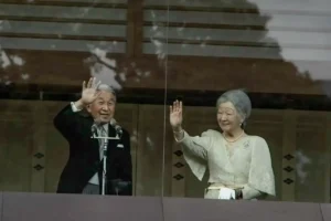 Emperor Akihito and Empress Michiko wave to well-wishers from a glass-enclosed balcony at the Imperial Palace.