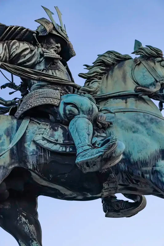 Detailed close-up of the weathered bronze Masashige Kusunoki statue, showing intricate samurai armor and textures.